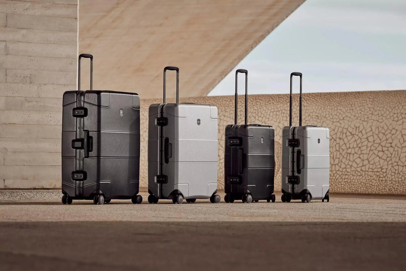 Four hardshell rolling suitcases lined up side by side.