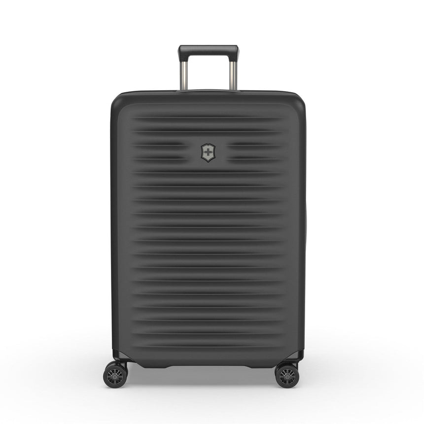 Black hardshell rolling suitcase with horizontal ridges and a retractable handle.