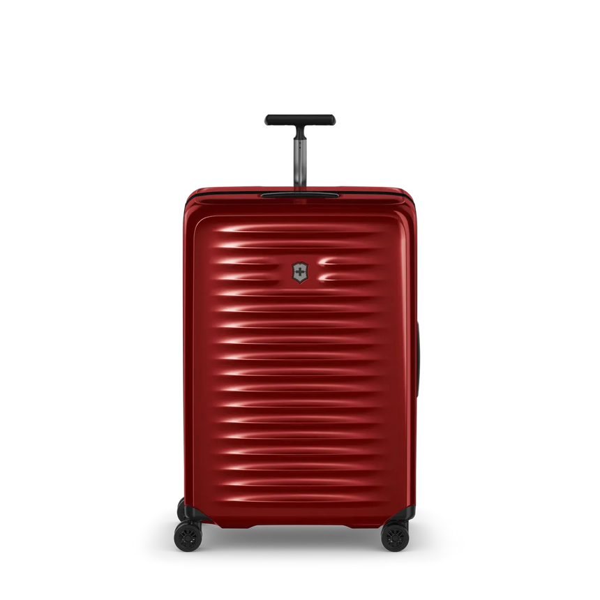Red hardshell rolling suitcase with horizontal ridges and a retractable handle.