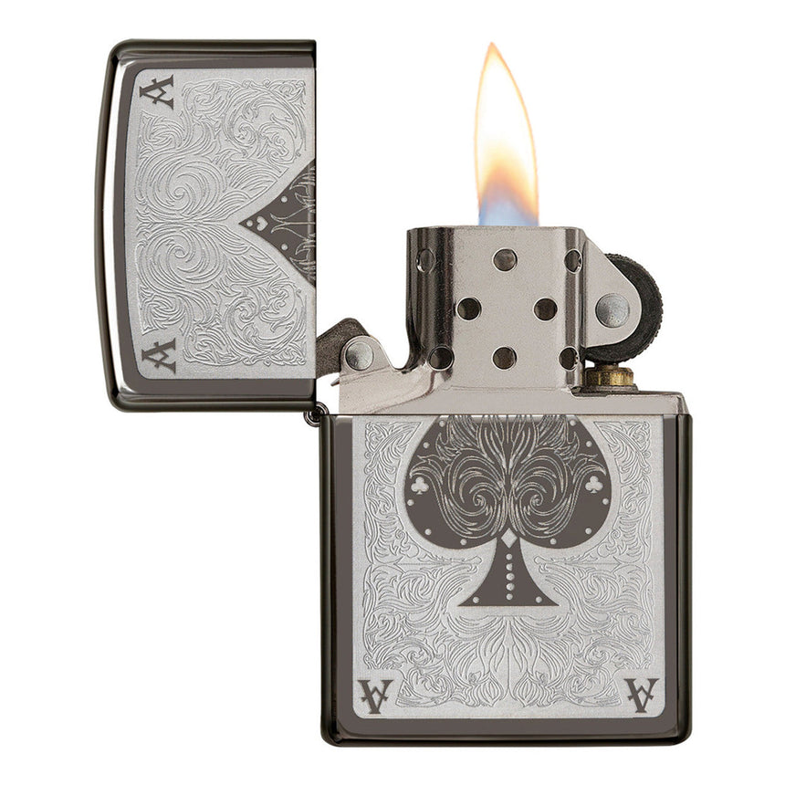 Ornate metal lighter with an engraved spade symbol and flame lit.