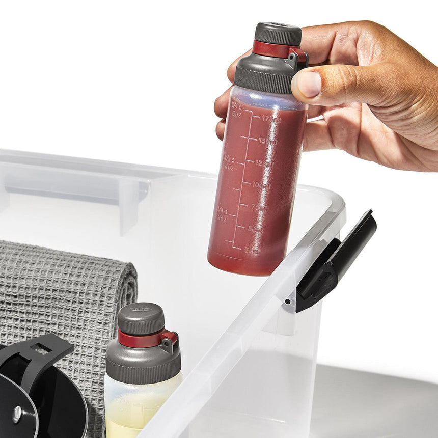 Reusable water bottle with measurement markings being held by a hand.