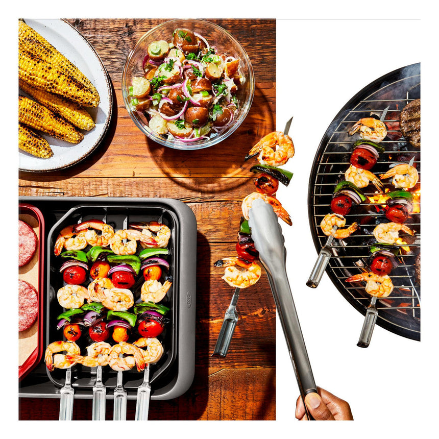 Assortment of grilled foods including corn, shrimp skewers, vegetable kebabs, and a fresh salad.