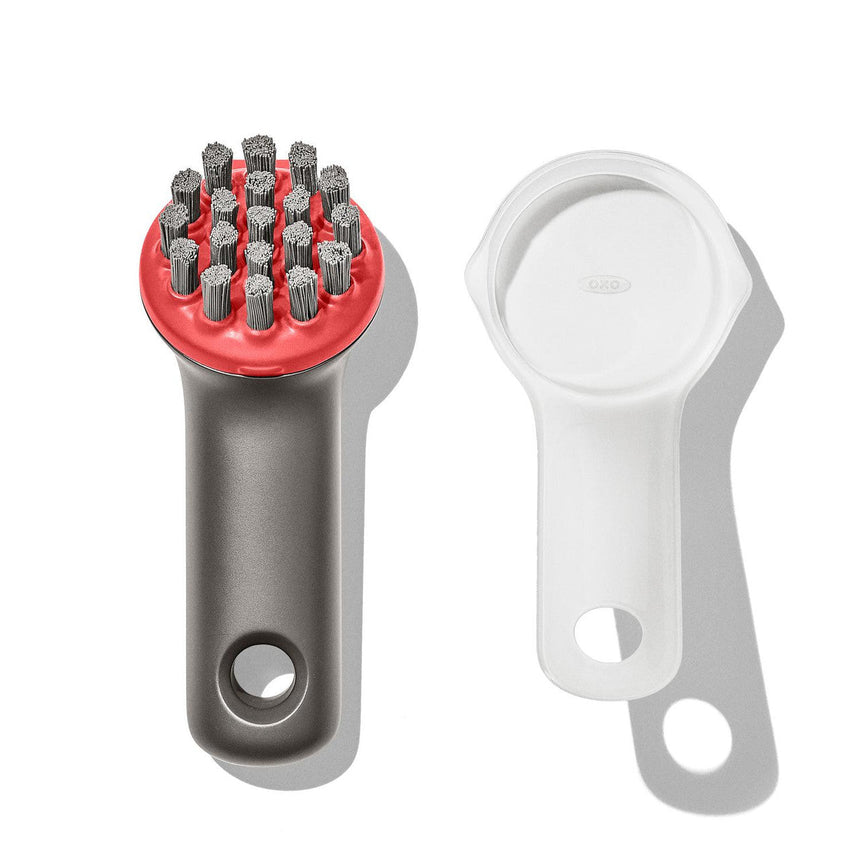 Handheld brush-like cleaning tool with metal bristles and a red plastic head.