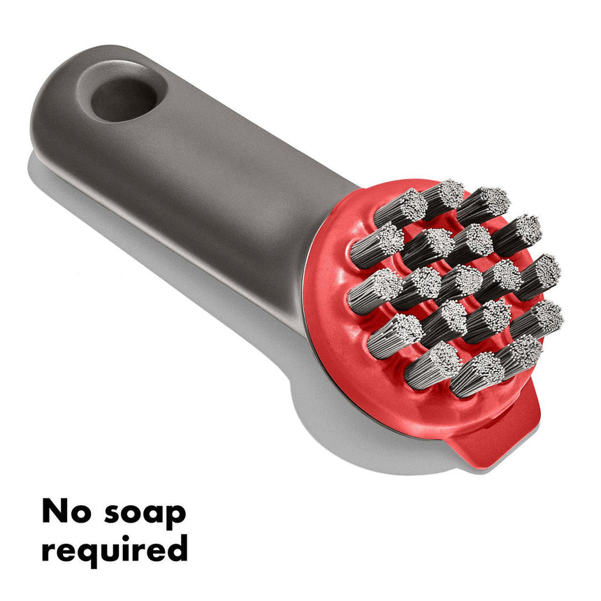Handheld scrubbing brush with metal bristles and a red plastic base.