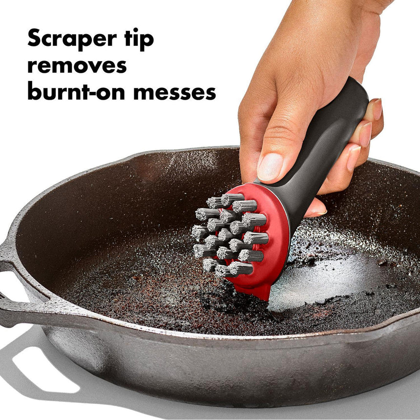 Scraper tool with a red handle and metal bristles for cleaning cookware.