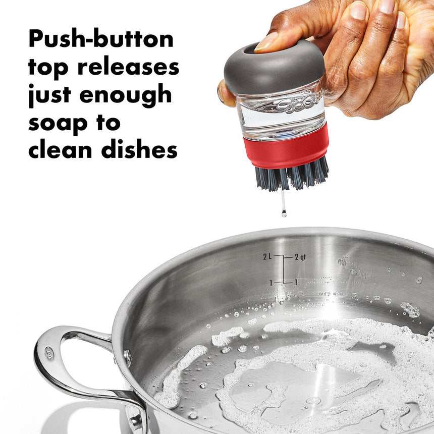 Dish scrubber brush with a soap-dispensing push-button top.