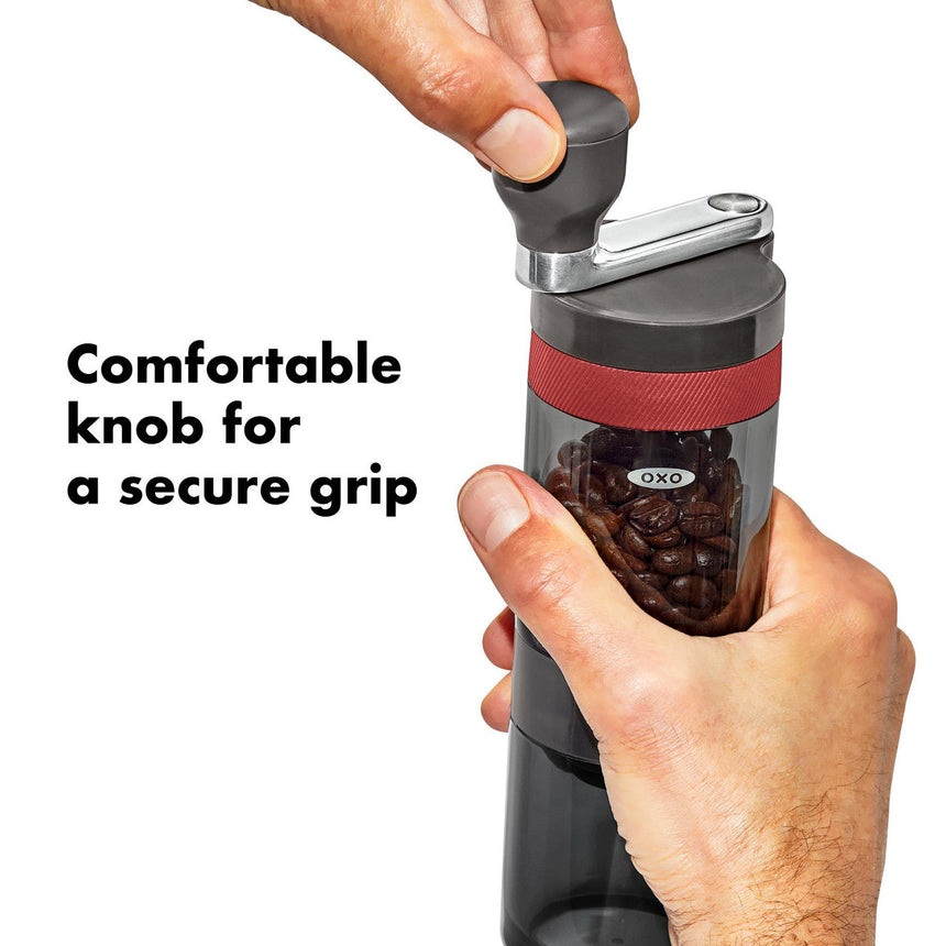 Manual coffee grinder with a transparent chamber containing coffee beans and a comfortable knob on top.