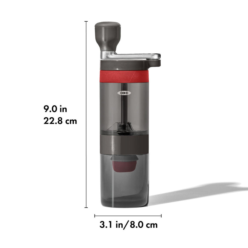 Manual coffee grinder with a transparent chamber and red accent band.