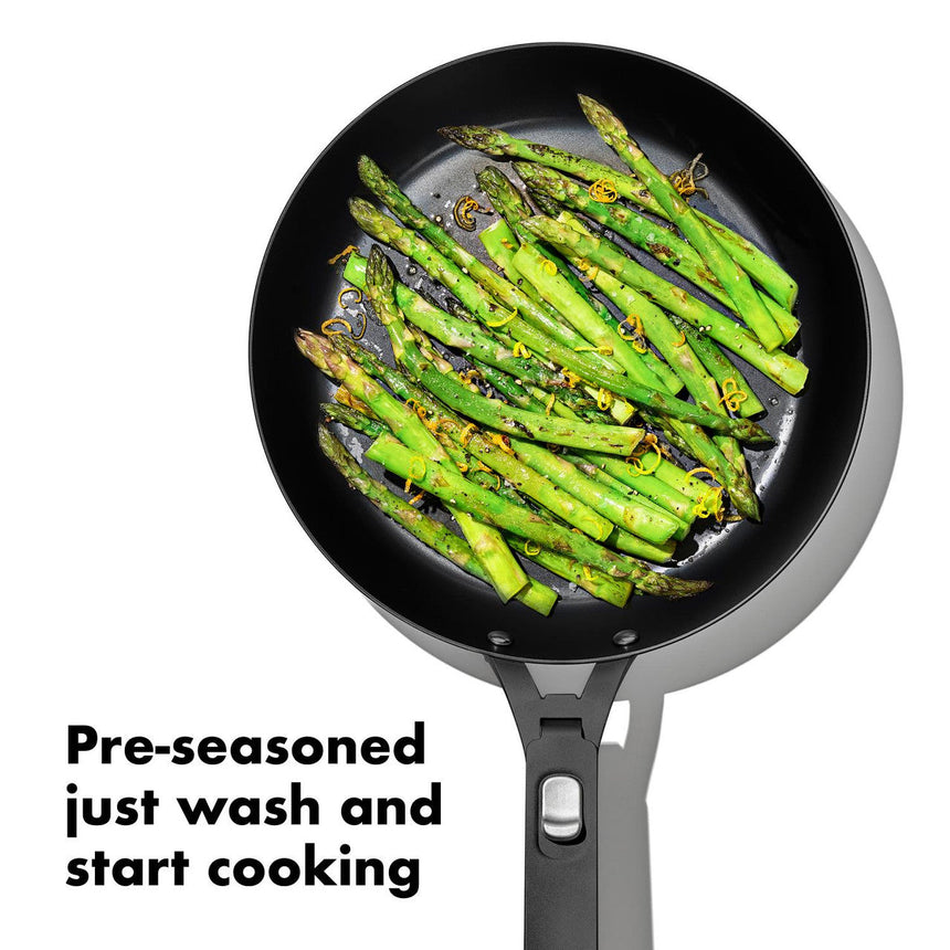 Frying pan containing bright green asparagus spears seasoned with herbs.