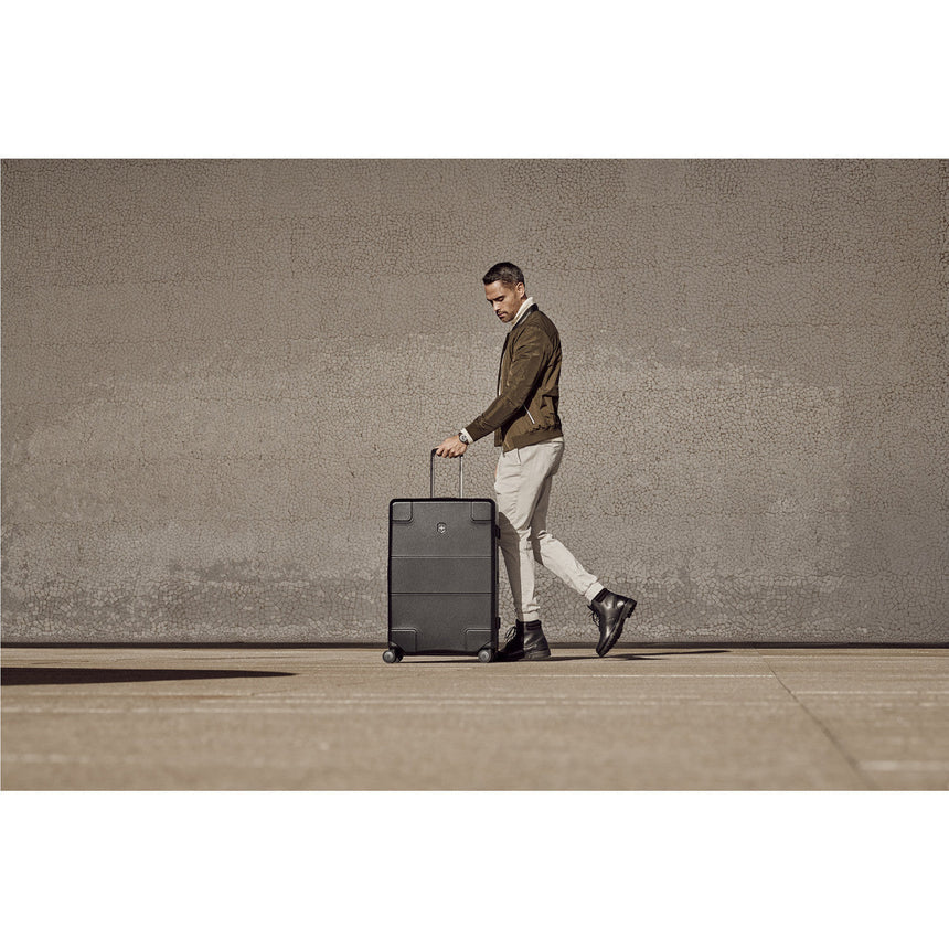 Wheeled suitcase being pulled by a stylishly dressed man.
