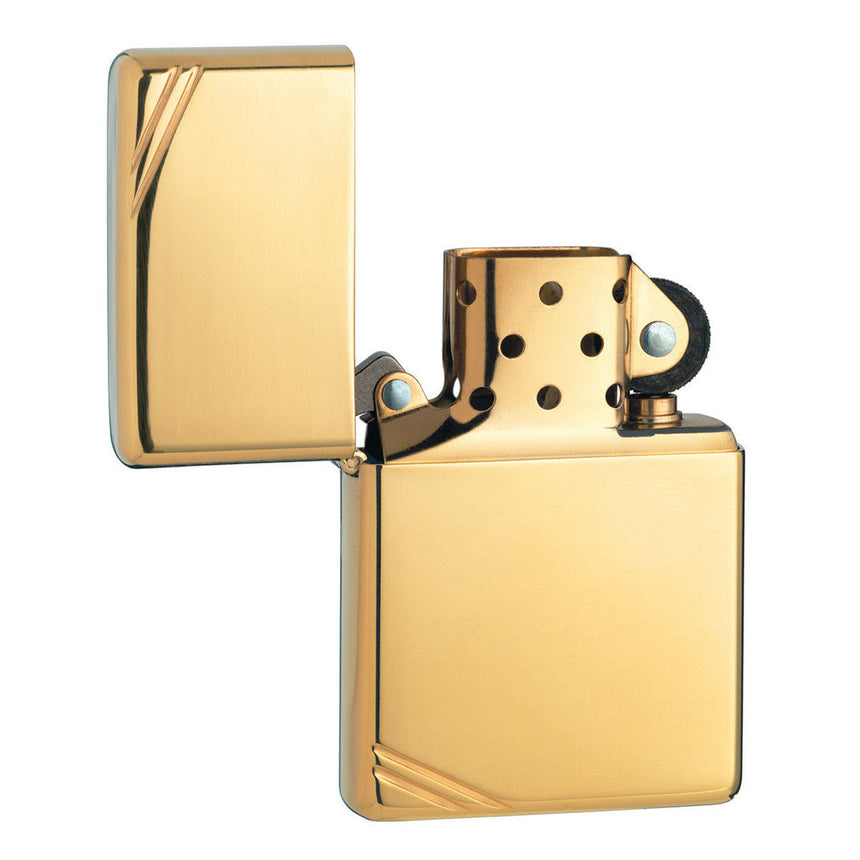Gold-colored metal flip lighter with decorative corner designs.