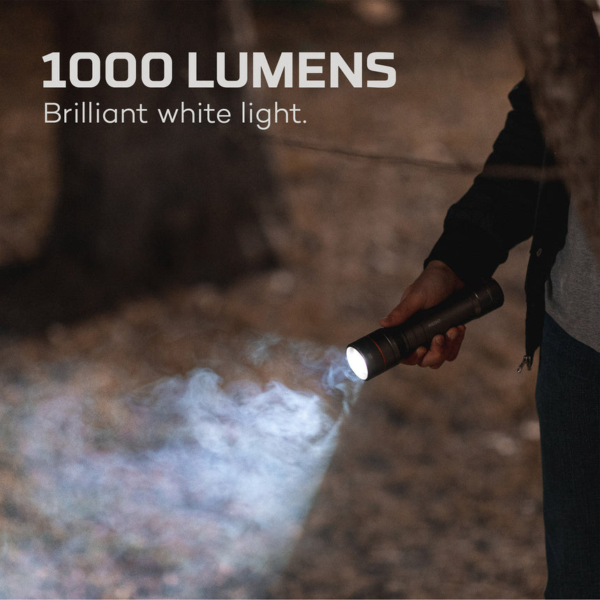 Handheld flashlight emitting an intense beam of white light in a smoky environment.