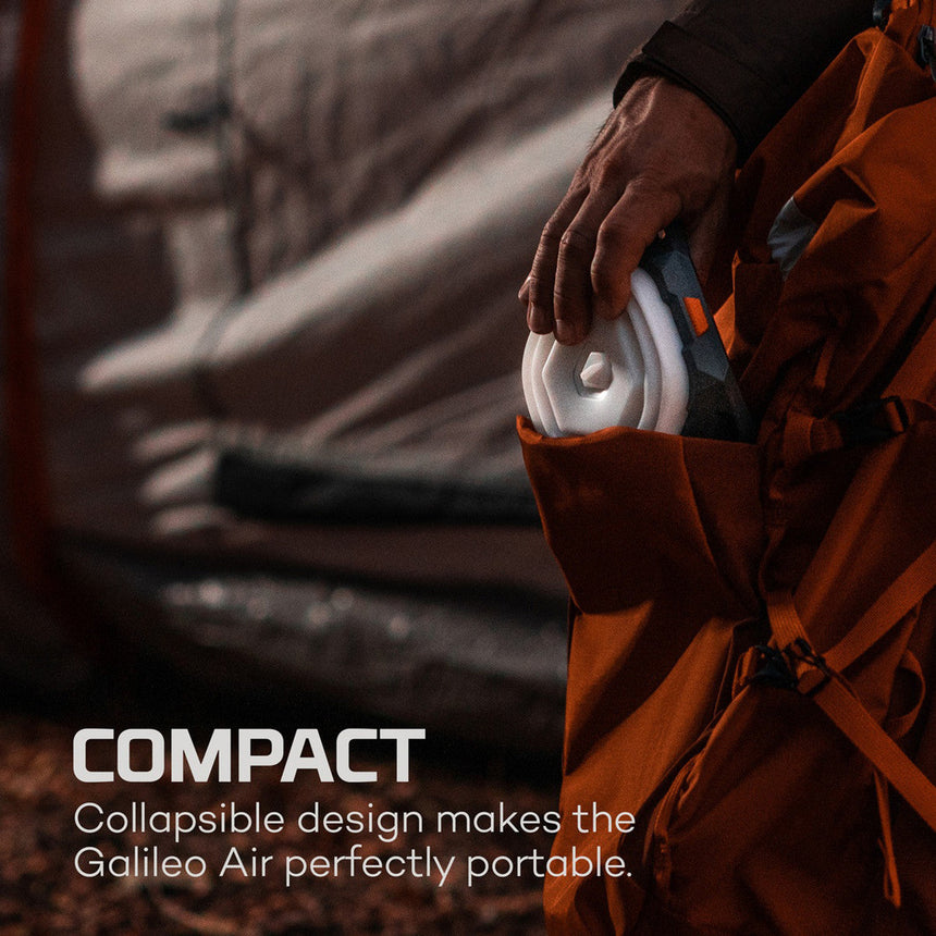 Collapsible white headphones or earphones being held against an orange fabric background.