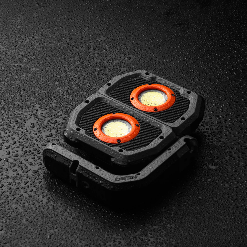 Compact dual-LED light with a rugged black housing and orange accents.