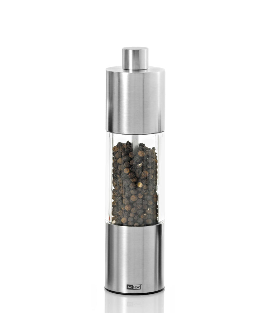 Stainless steel and glass pepper mill or grinder filled with peppercorns.