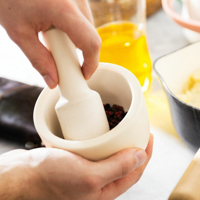 Mortar and pestle with dark spices or herbs inside.