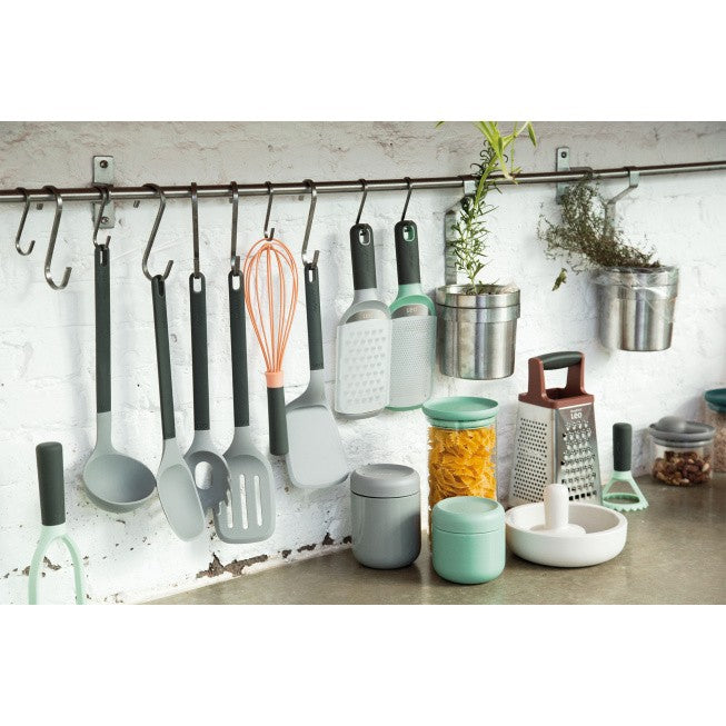 Kitchen utensils and accessories hanging on a rail and arranged on a counter.