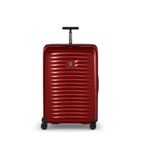 Red hardshell rolling suitcase with horizontal ridges and a retractable handle.