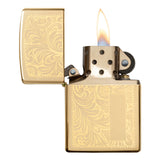 Gold-colored Zippo lighter with an ornate floral engraving pattern, shown open with a flame lit.