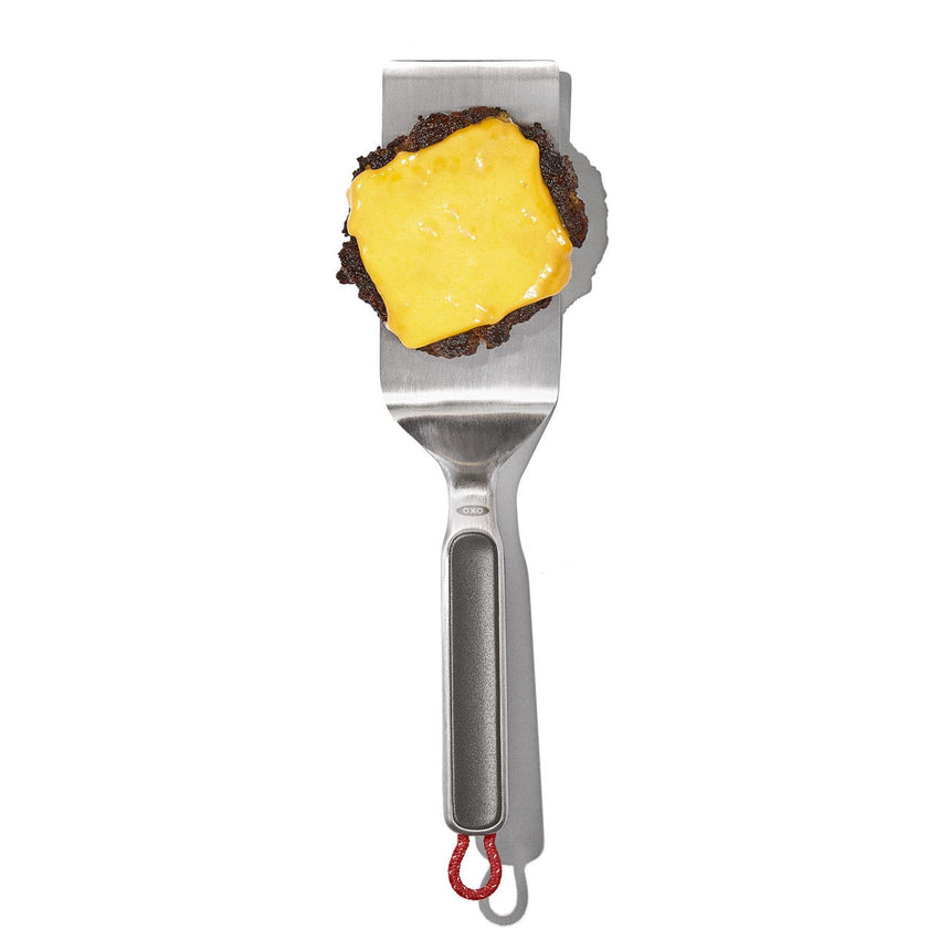 Stainless steel cheese slicer with a square piece of cheese on its blade.
