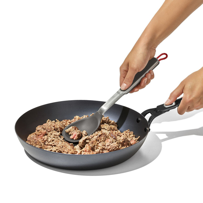 Frying pan containing ground meat being stirred with a spatula.