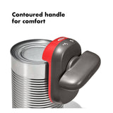Electric can opener with a contoured handle attached to a metal can.