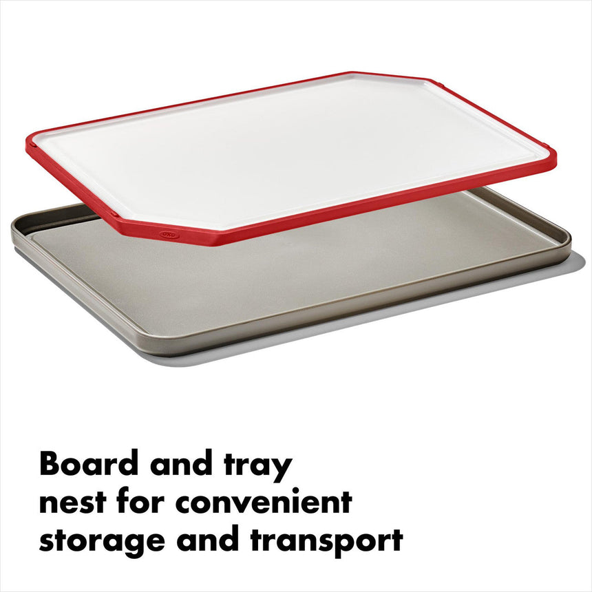 Cutting board with red trim sitting atop a metal baking sheet.