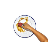 White plate with a blue rim containing a smear of yellow sauce and a hand holding a red-tipped utensil.