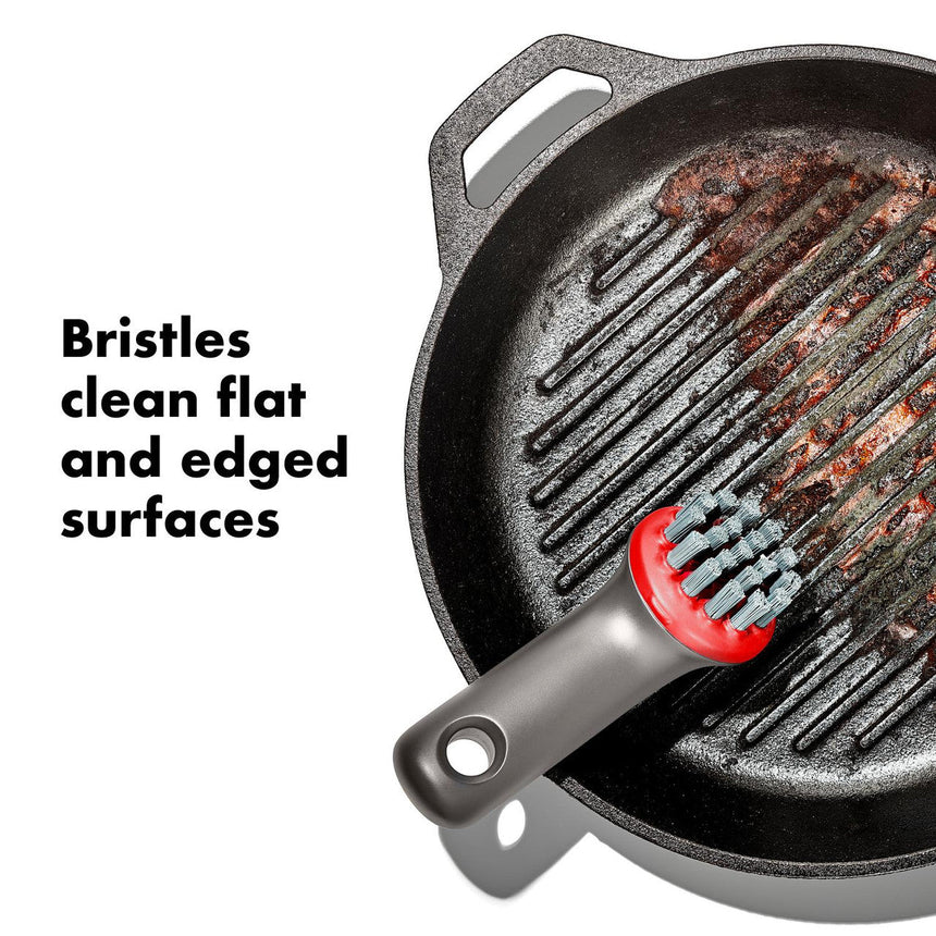 Cast iron grill pan with a cleaning brush featuring bristles designed for flat and edged surfaces.