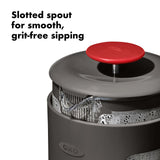 French press coffee maker with a slotted spout and red lid.