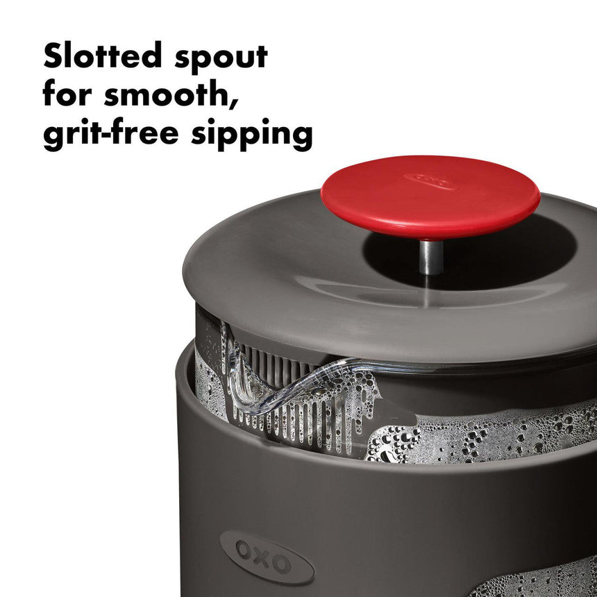 French press coffee maker with a slotted spout and red lid.