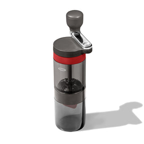 Manual coffee grinder with a transparent body and red accent band.
