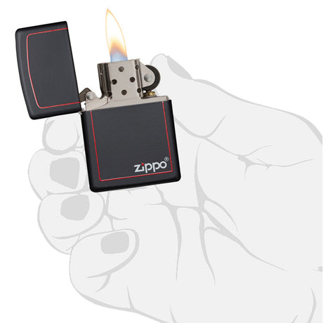 Lit Zippo lighter with black casing and red trim held in a hand.