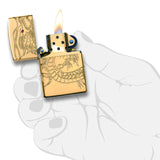 Gold-colored Zippo lighter with an engraved dragon design, lit with a flame.