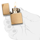 Gold-colored metal lighter with an open lid and lit flame.