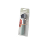Handheld pet grooming brush with a mint green handle in retail packaging.