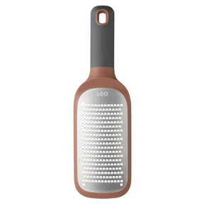 Kitchen grater with a rose gold-colored handle and gray grating surface.