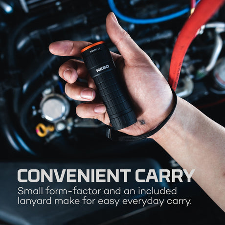 Handheld flashlight with a lanyard attached, held in a person’s hand.