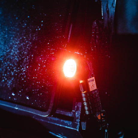 Red traffic light glowing brightly in the darkness.