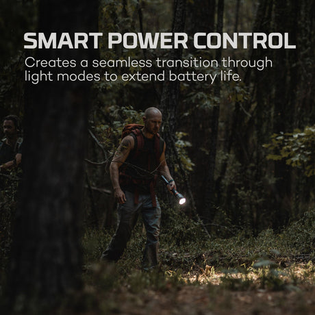 Person hiking in a dark forest while using a flashlight.