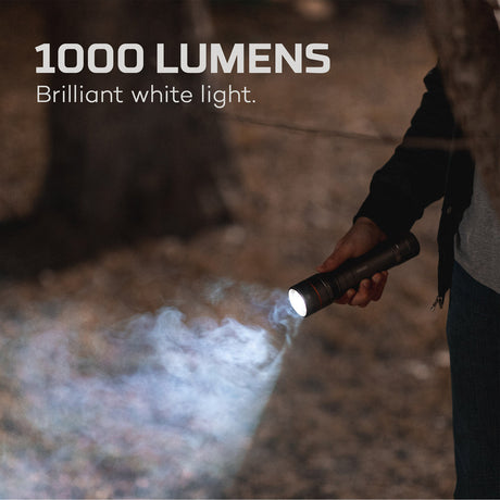 Handheld flashlight emitting an intense beam of white light in a smoky environment.
