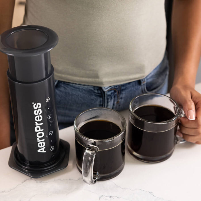 AeroPress coffee maker with two cups of brewed coffee.