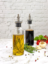 Glass bottles containing olive oil and balsamic vinegar with herbs and spices.