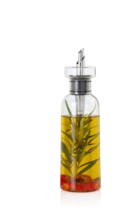 Glass bottle containing yellow oil with herbs and red peppers infused inside.
