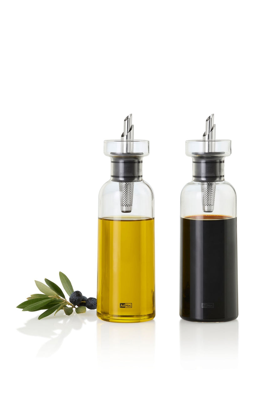 Two glass bottles containing olive oil and balsamic vinegar with pouring spouts.