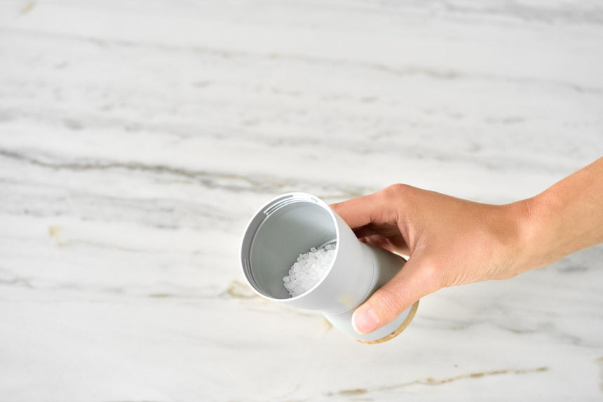 Hand holding a white ceramic coffee mug or cup.