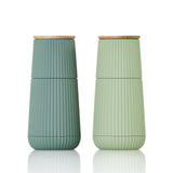 Two ribbed ceramic travel mugs with wooden lids in sage green and mint colors.