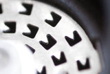 Perforated metal surface with arrow-shaped holes.