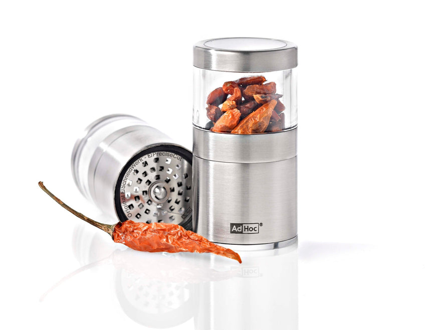 Stainless steel spice grinder with a clear container holding dried chili peppers.