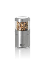 Stainless steel and glass spice grinder filled with peppercorns.